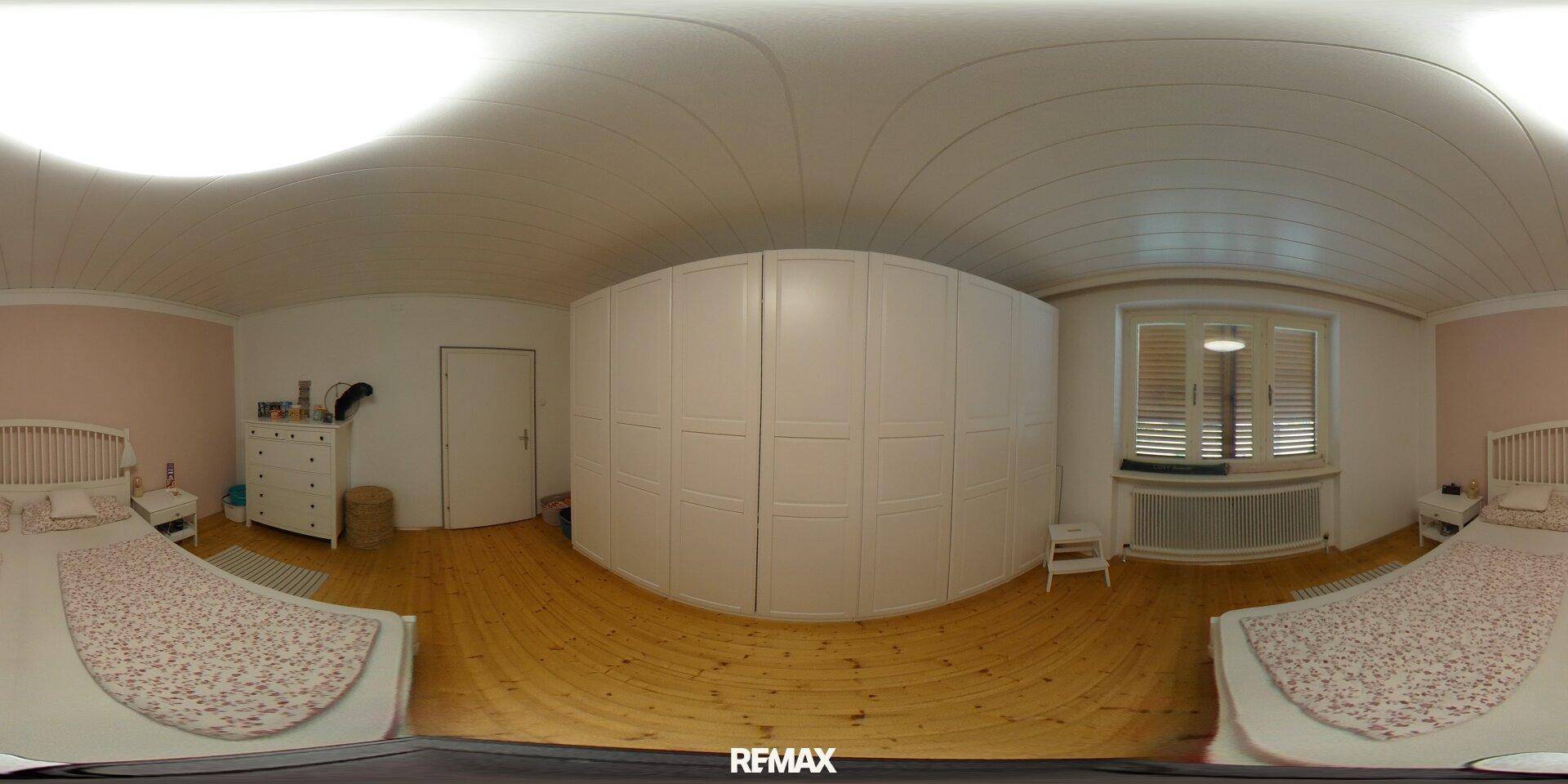 Schlafzimmer mit Doppelbett, großem Kleiderschrank und Holzboden.