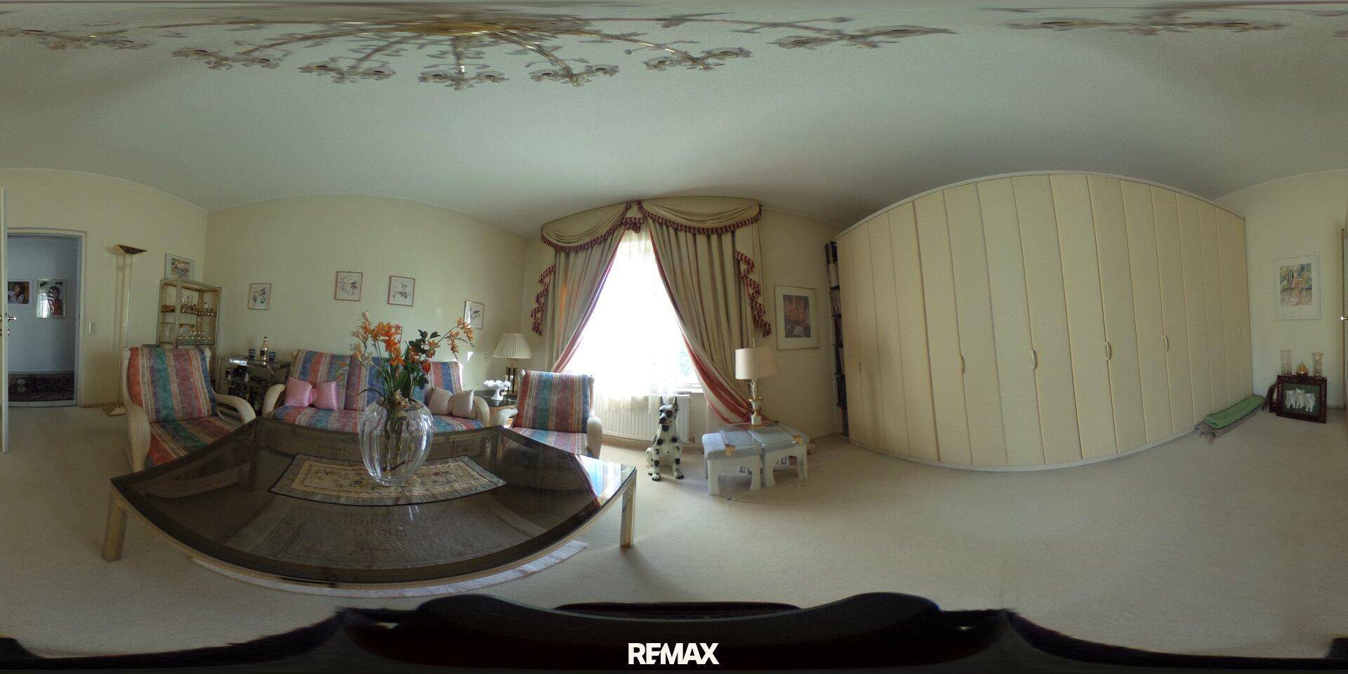 Helles Wohnzimmer mit Sofa, Couchtisch und großem, geschwungenem Einbauschrank.