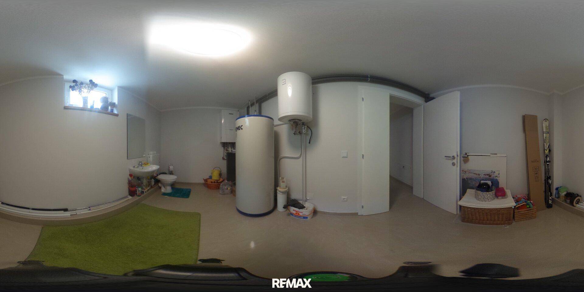 Technikraum im Keller mit Warmwasserspeichern, Waschbecken und einfacher Toilette.