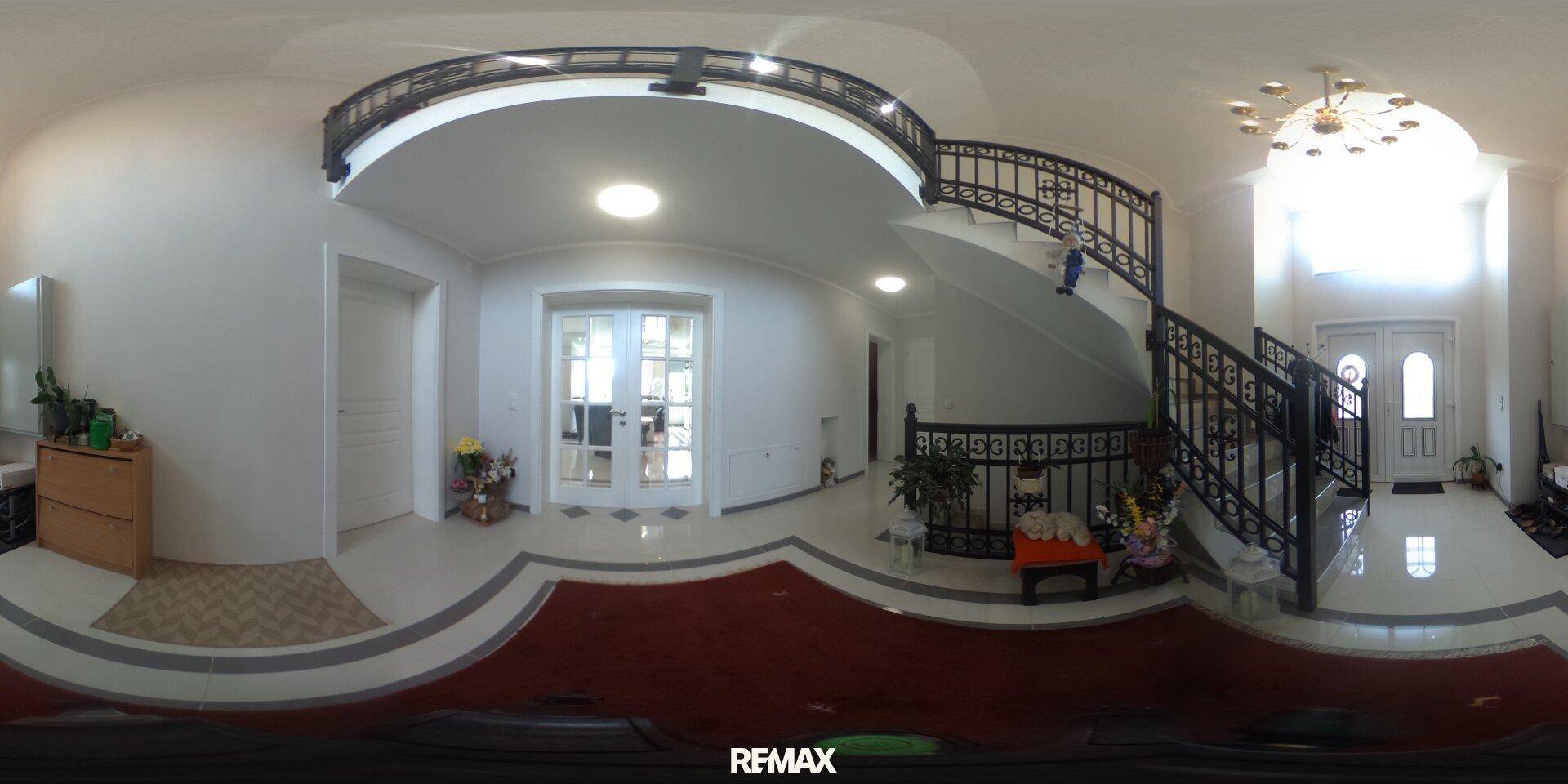 Eindrucksvolle Eingangshalle mit geschwungener Treppe, hohen Decken und eleganten Säulen.