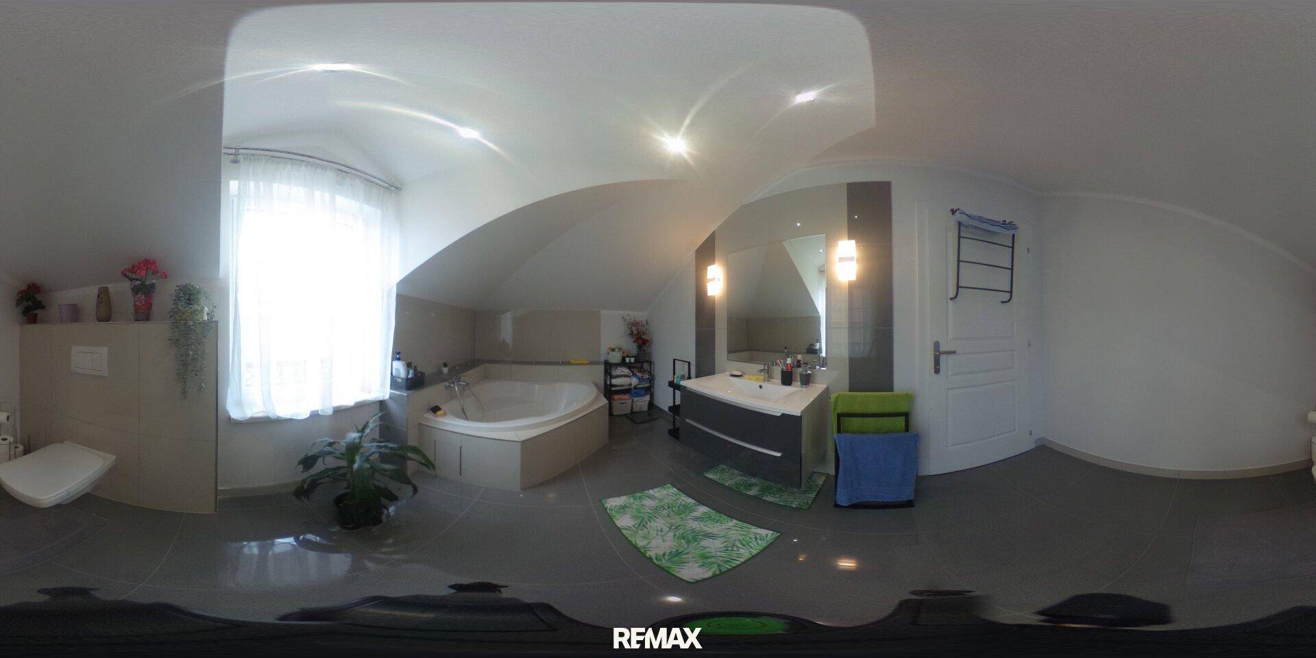 Geräumiges Badezimmer im Dachgeschoss mit Eckbadewanne und modernem Waschtisch.