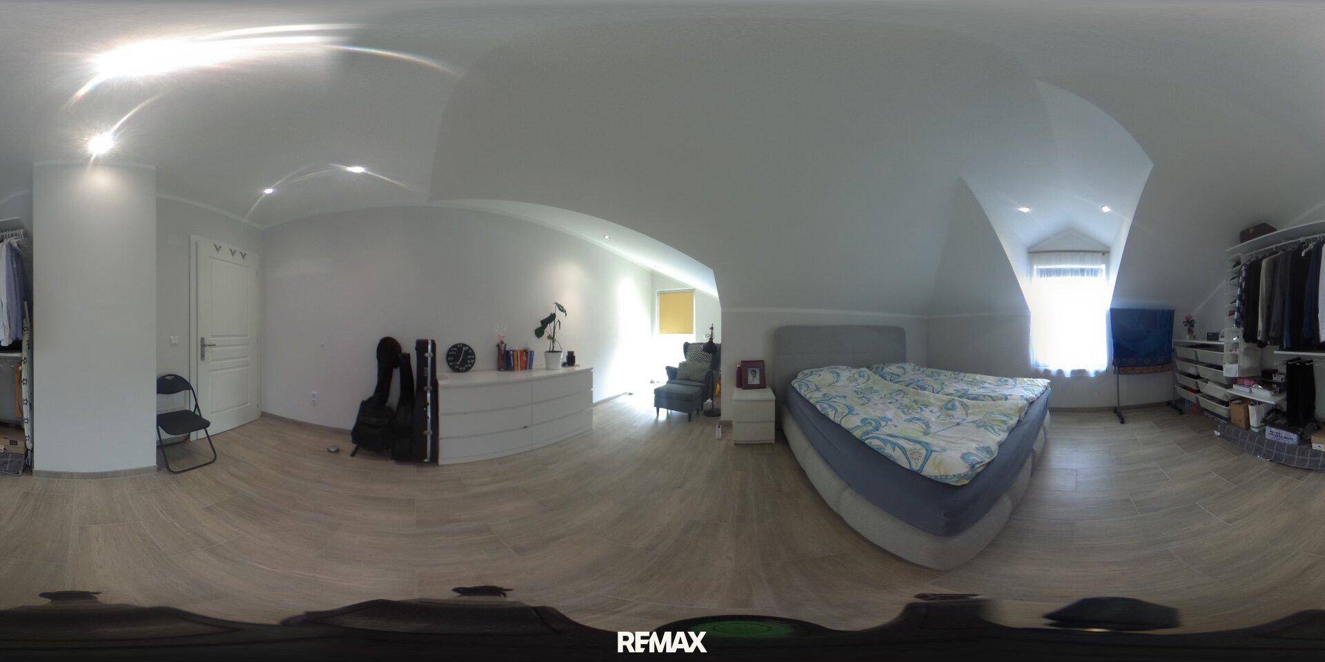 Helles Dachschlafzimmer mit großem Bett, Dachschrägen und integrierten Schränken.