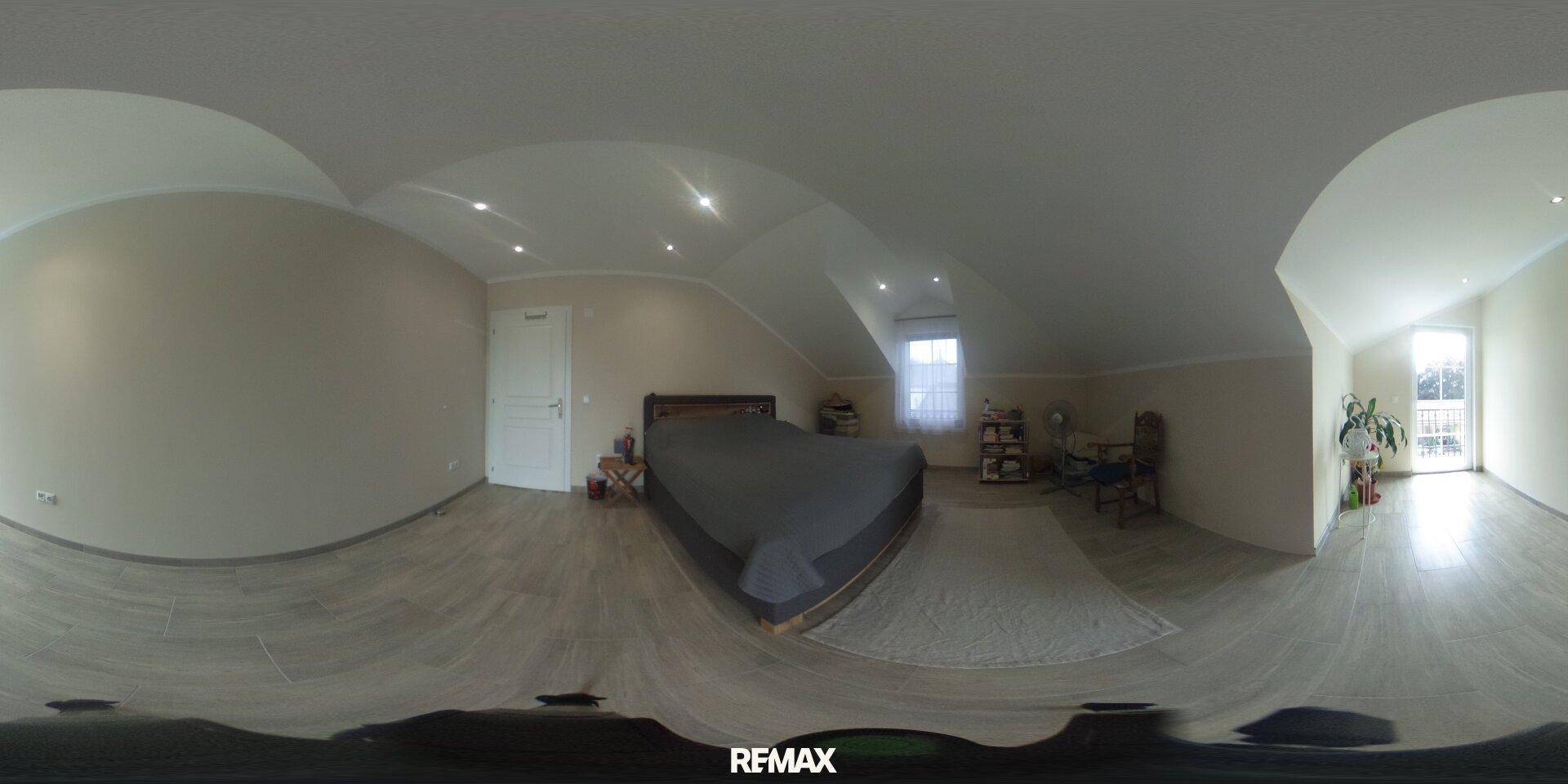 Geräumiges Schlafzimmer im Dachgeschoss mit Dachschrägen und hellem Fenster.
