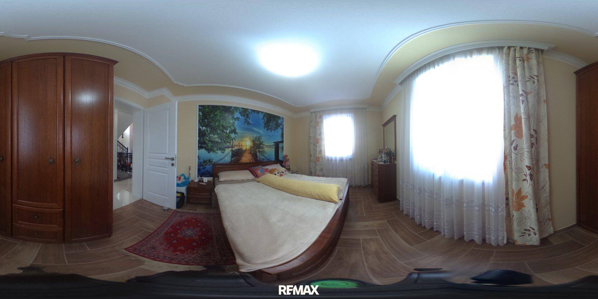 Gemütliches Schlafzimmer mit Holzboden, großem Bett und floraler Wanddekoration.