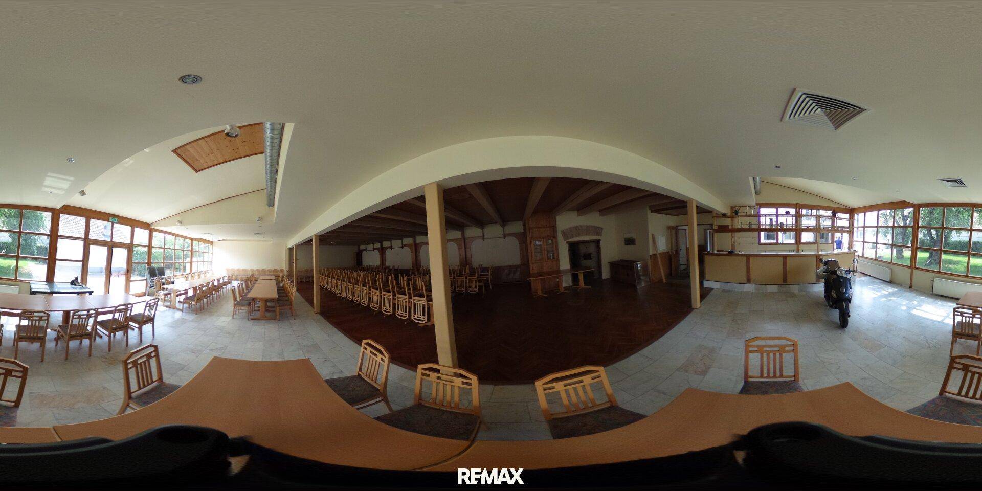 360-Grad-Panorama eines großen Speisesaals mit vielen Tischen, Stühlen und großen Fenstern.