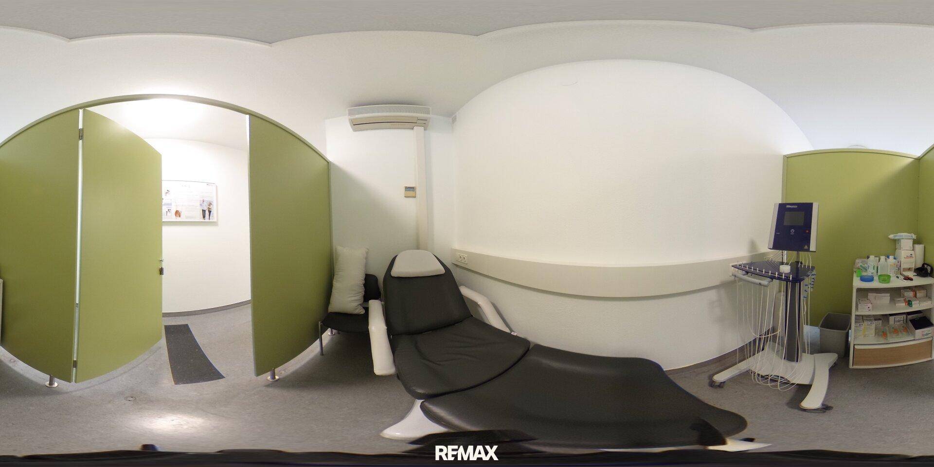 Panoramaansicht eines Behandlungsraums mit grünem Paravent, Behandlungsstuhl und medizinischen Geräten, sauber und hell.
