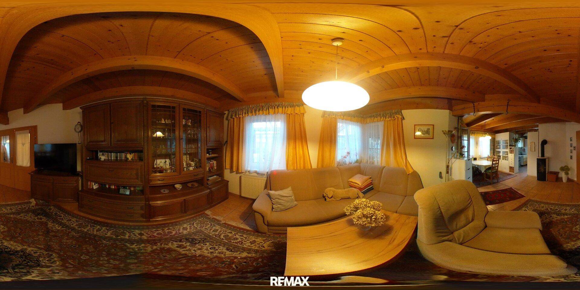 Gemütliches Wohnzimmer mit Holzdecke, Teppichboden und traditionellen Möbeln.