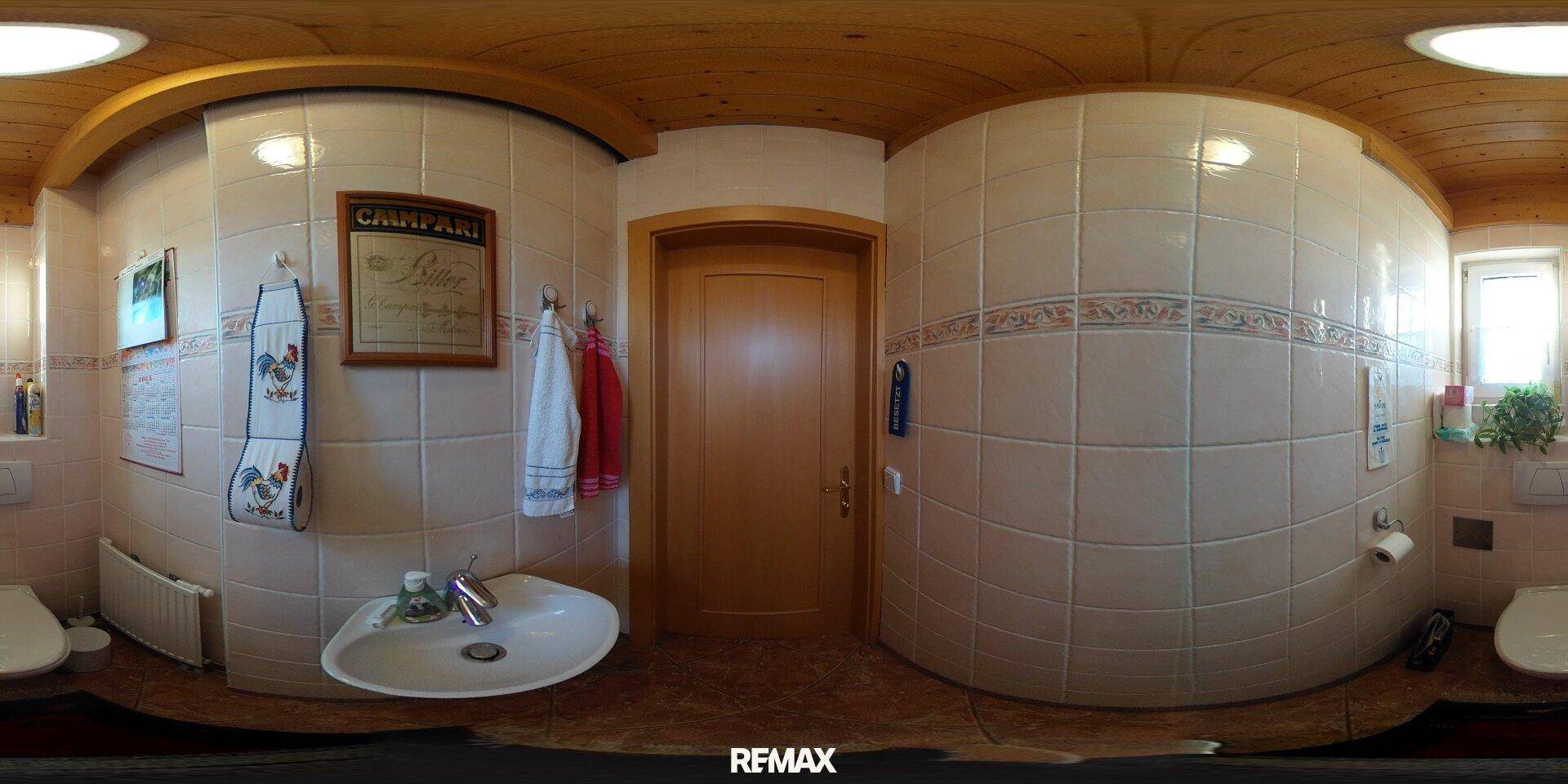 Helles Badezimmer mit beigefarbenen Fliesen, Waschbecken und Fenster.