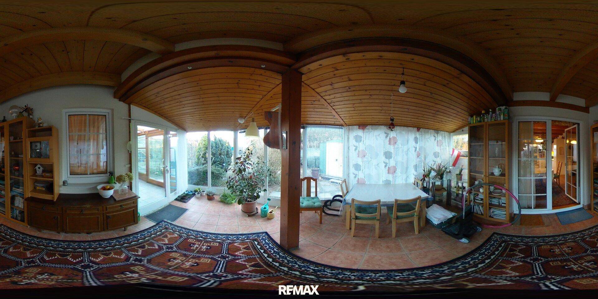 Heller Wintergarten mit Essbereich, Pflanzen und Zugang zum Garten.