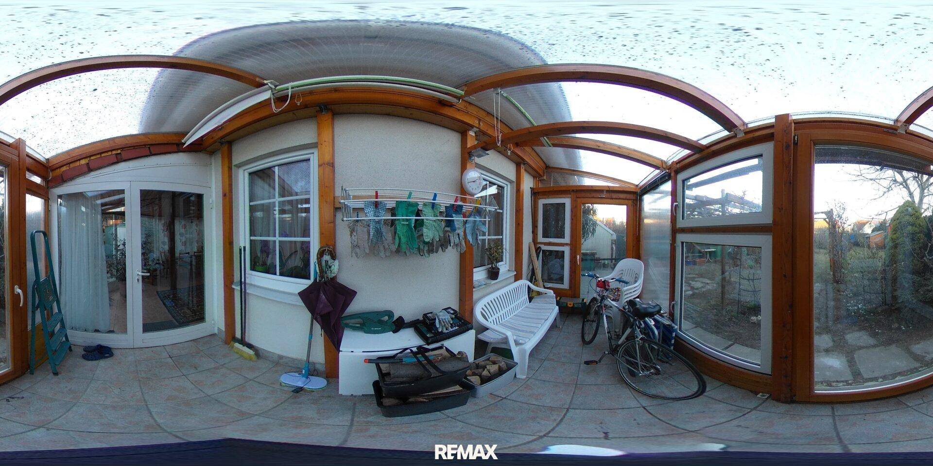 Überdachte Terrasse mit Wäscheständer, Sitzbank und Blick ins Grüne.