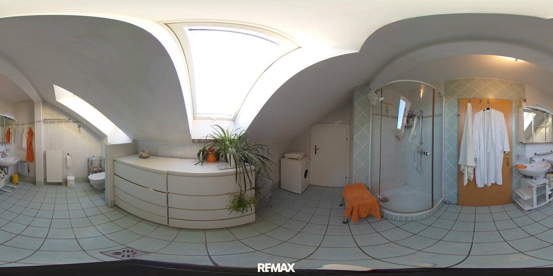 Helles Badezimmer im Dachgeschoss mit Dusche, Waschmaschine und Dachfenster.
