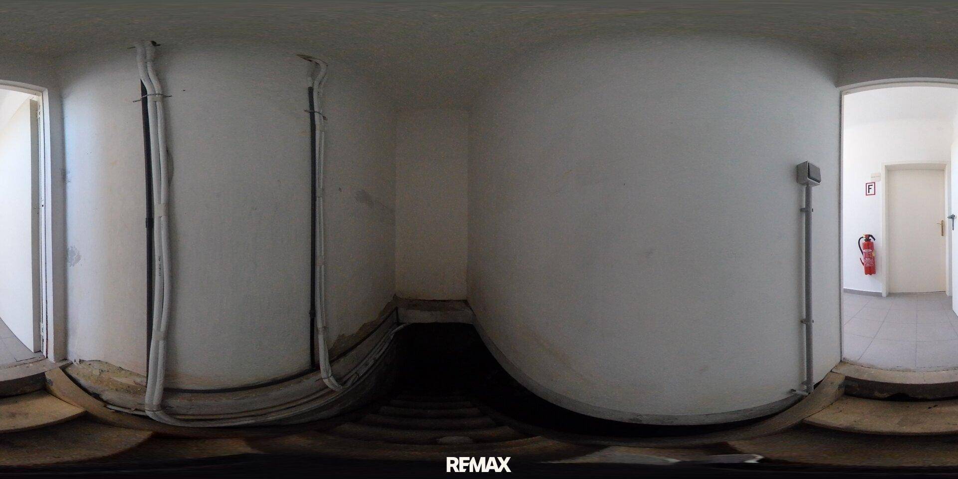 Panoramablick auf einen einfachen Raum mit sichtbaren Rohren und hellen Wänden.