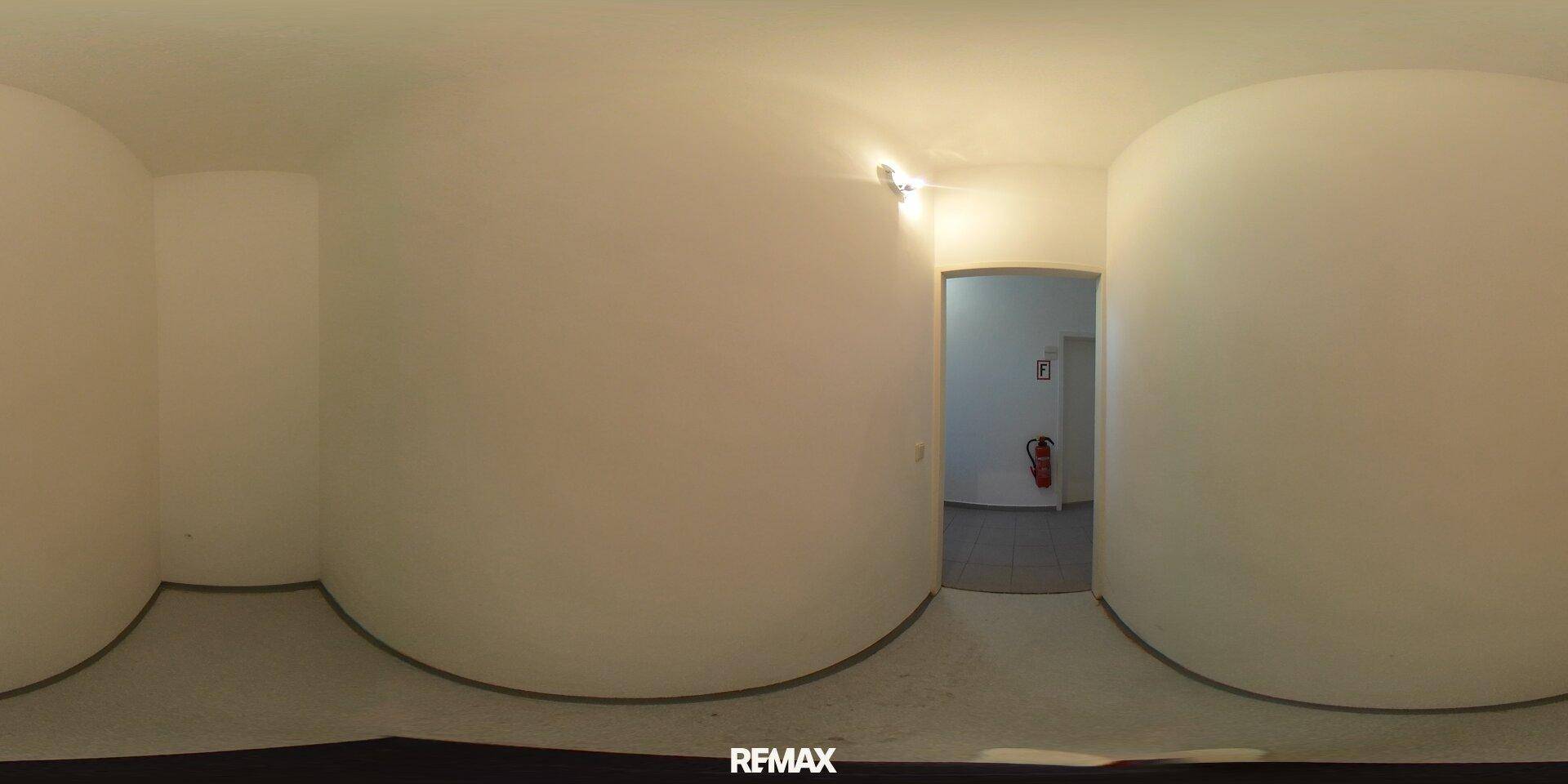 Panoramablick auf einen schlichten Flur mit hellen Wänden und einem Eingang zu einem weiteren Raum.