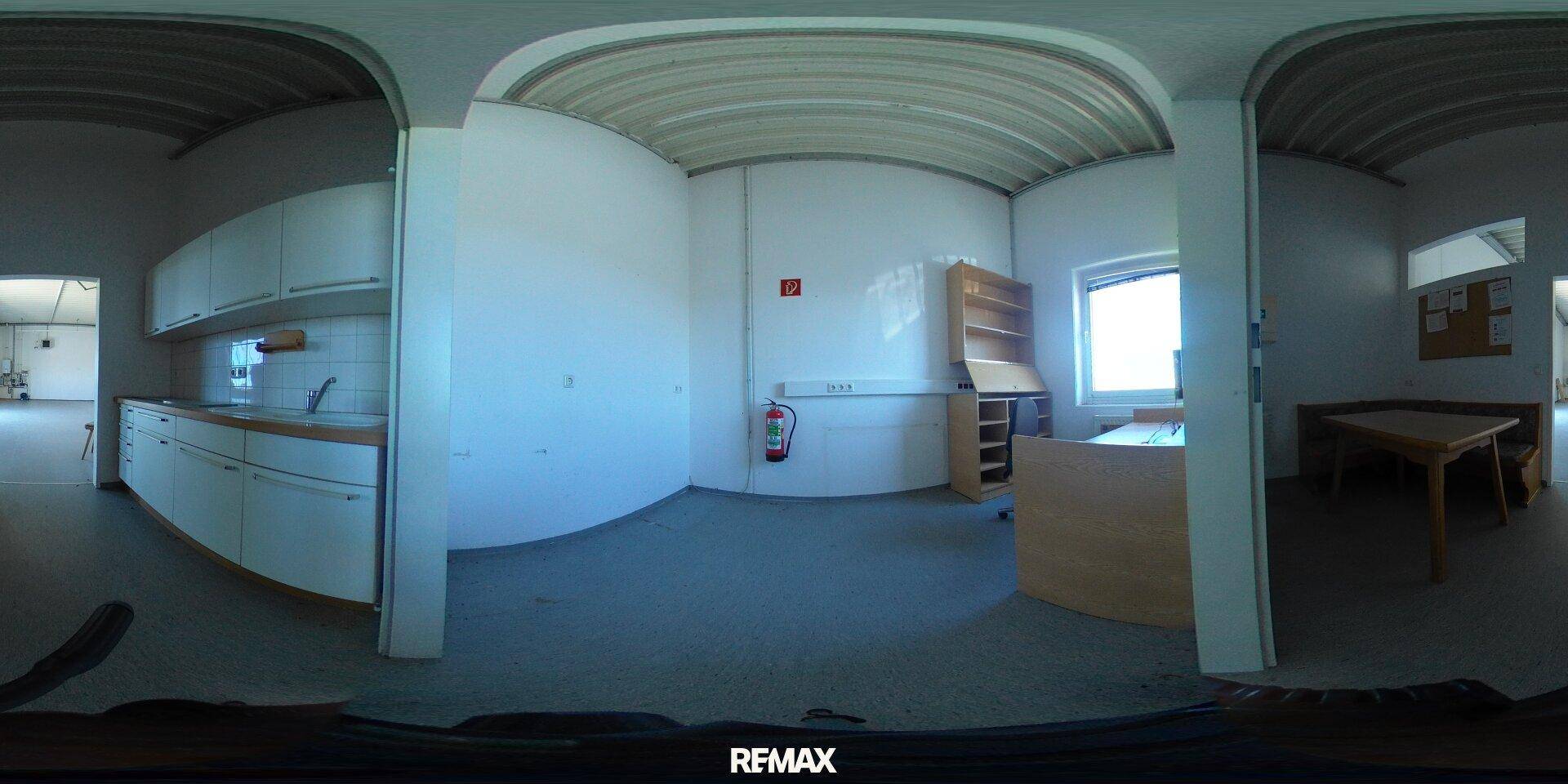 Panoramablick auf einen Innenraum mit einer kleinen Küchenzeile, einem Bürobereich und einem Esstisch.