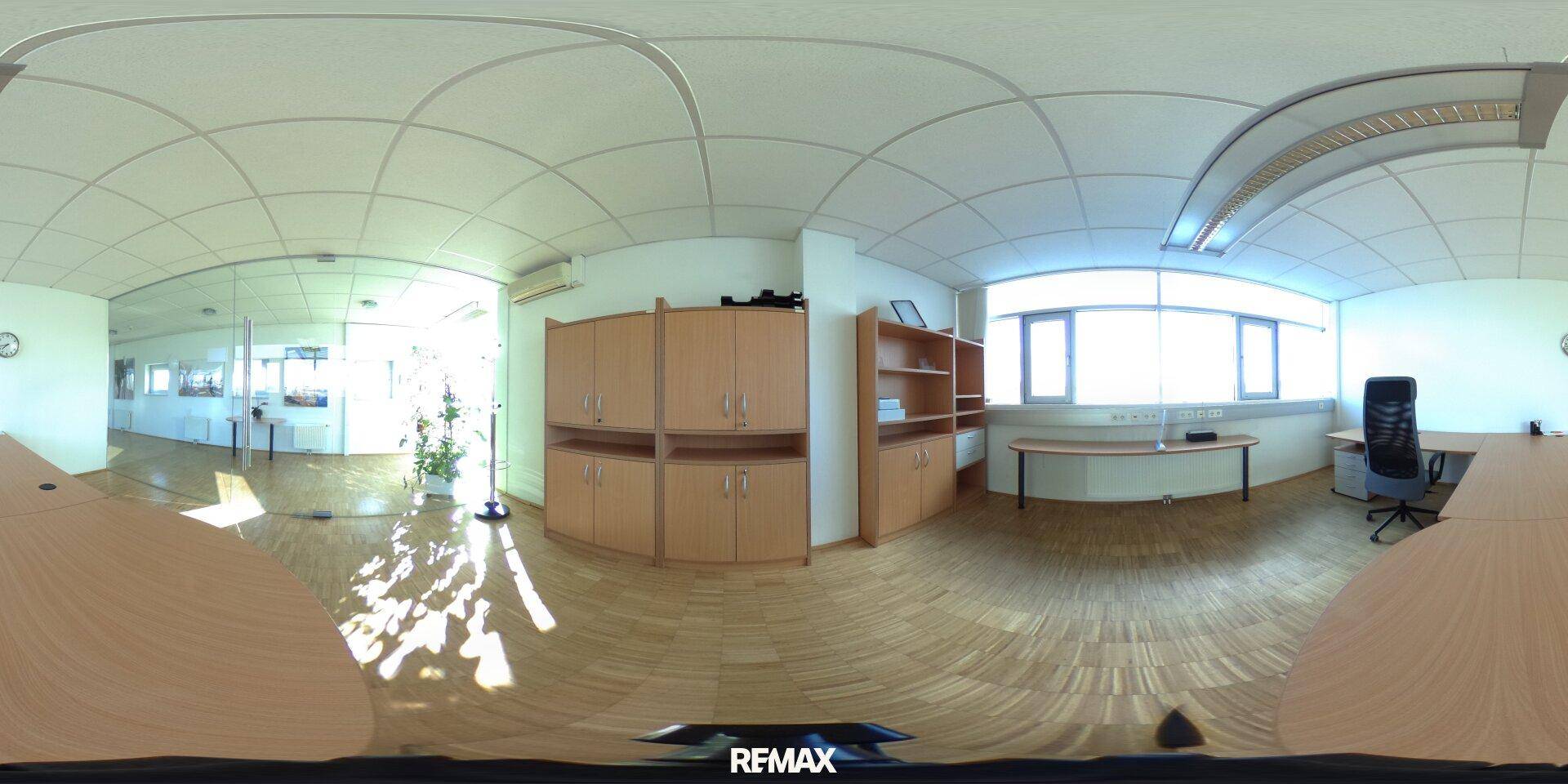 Helles Büro mit Holzfußboden, Schränken und einem Schreibtisch, gut beleuchtet durch Fenster.