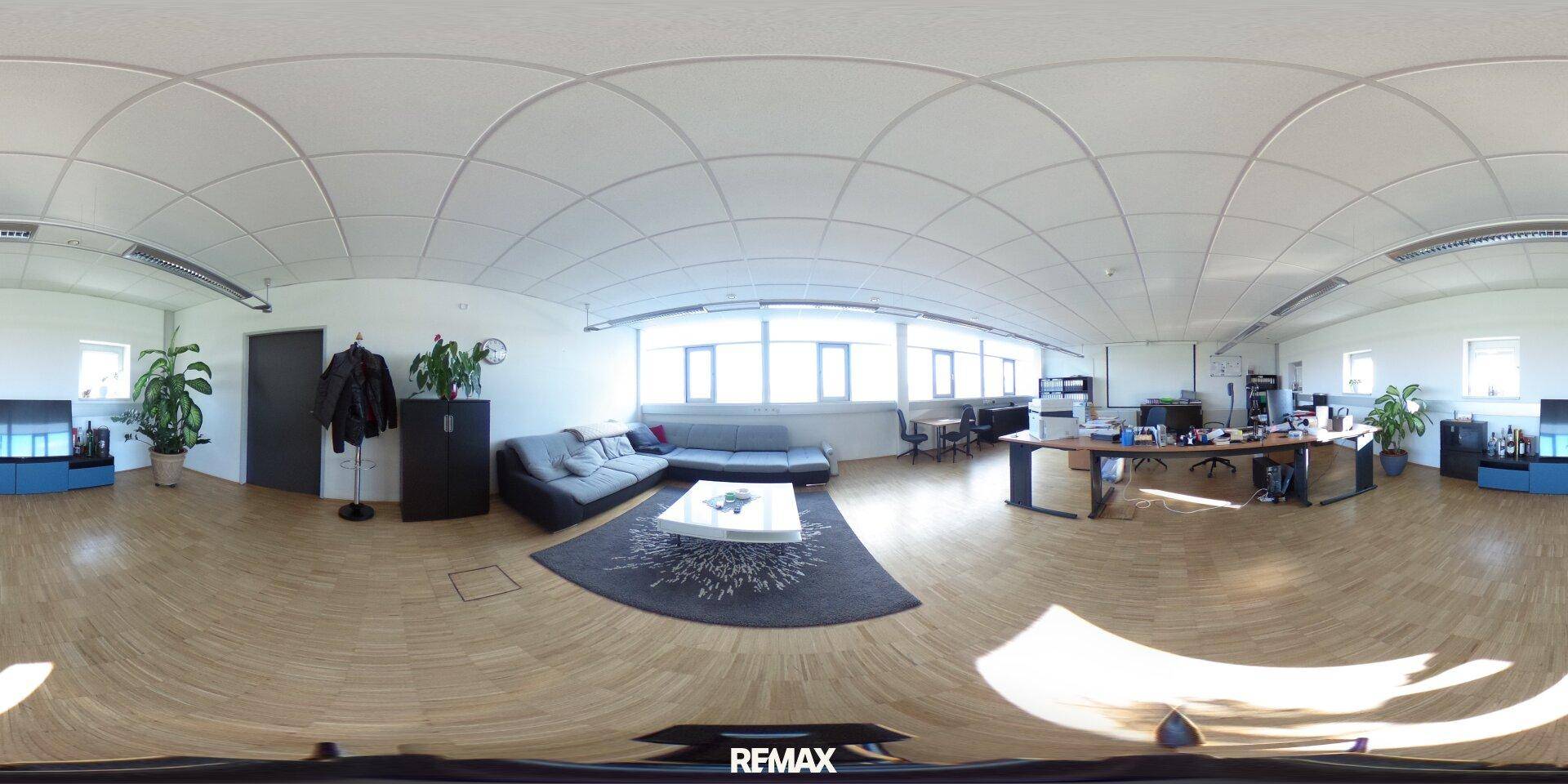 Großraumbüro mit Holzfußboden, bequemen Sofas und mehreren Arbeitsplätzen, hell und geräumig.