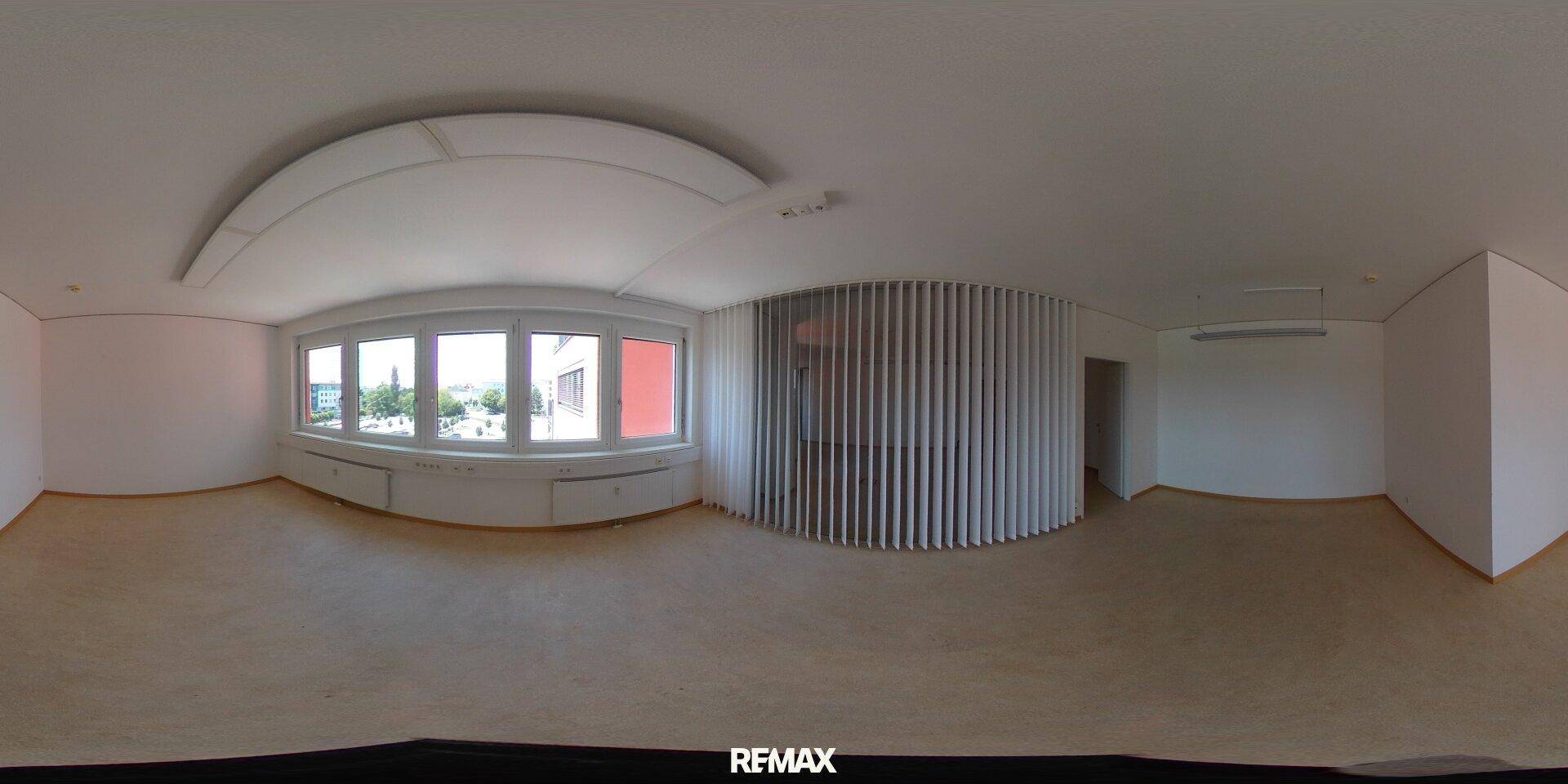 Panoramaaufnahme eines hellen Büros mit großen Fenstern und einem modernen Lamellenvorhang.
