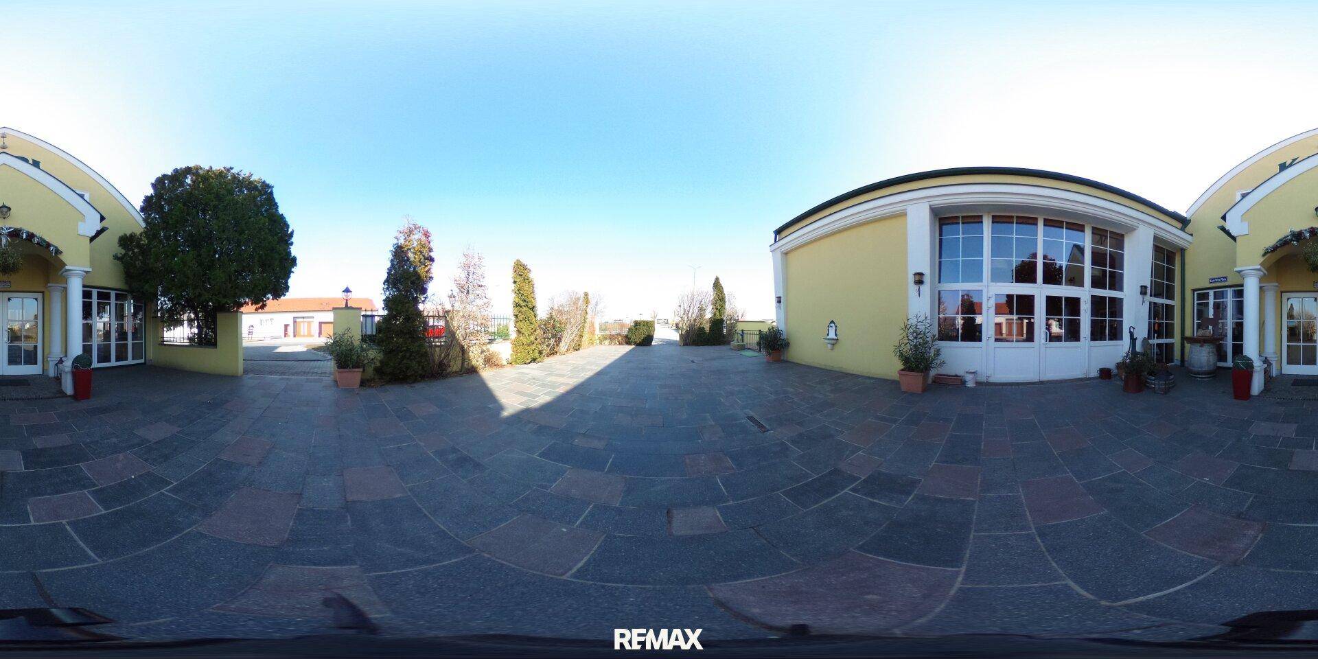 Weitläufiger gepflasterter Vorplatz mit Gebäudefassaden und klarem Himmel, ideal für Veranstaltungen.