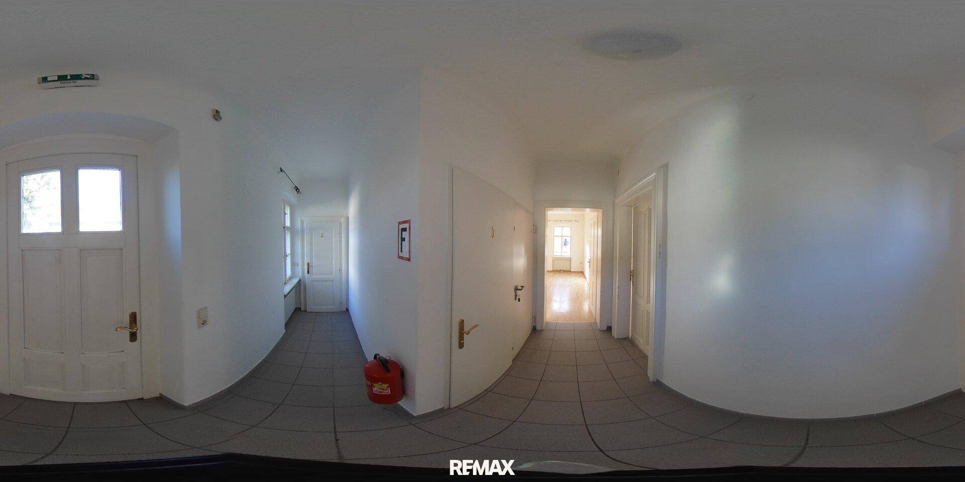 360-Grad-Innenansicht eines hellen Flurs mit Fliesenboden und weißen Wänden, der zu weiteren Räumen führt.