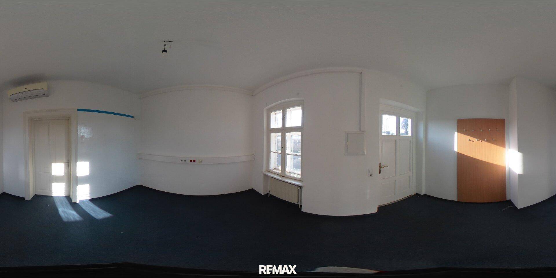 Raum mit dunklem Teppichboden, einem Fenster, einer Tür und einer Holzverkleidung.