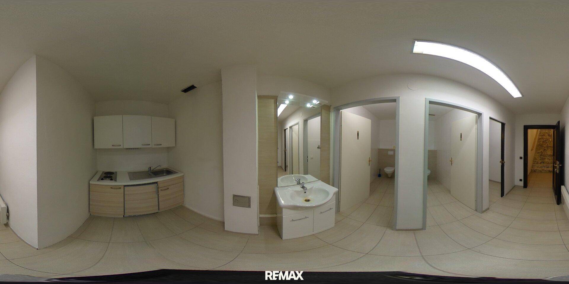 Panoramaansicht einer kleinen Küchenzeile und mehrerer Toilettenräume mit modernen Armaturen.