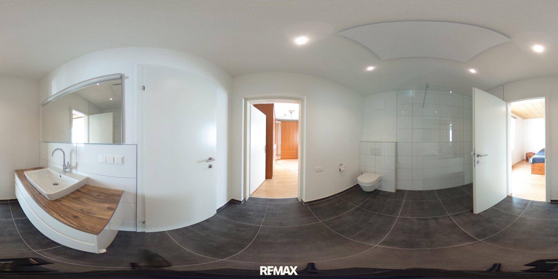 Helles Badezimmer mit modernem Einzelwaschbecken, Toilette und Zugang zu weiteren Räumen.
