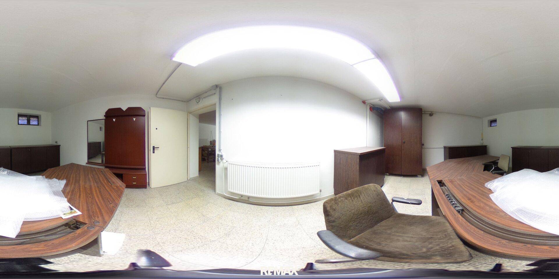 Heller Kellerraum, eingerichtet als Hobbyraum oder Büro, mit Heizkörper und Holzmöbeln.