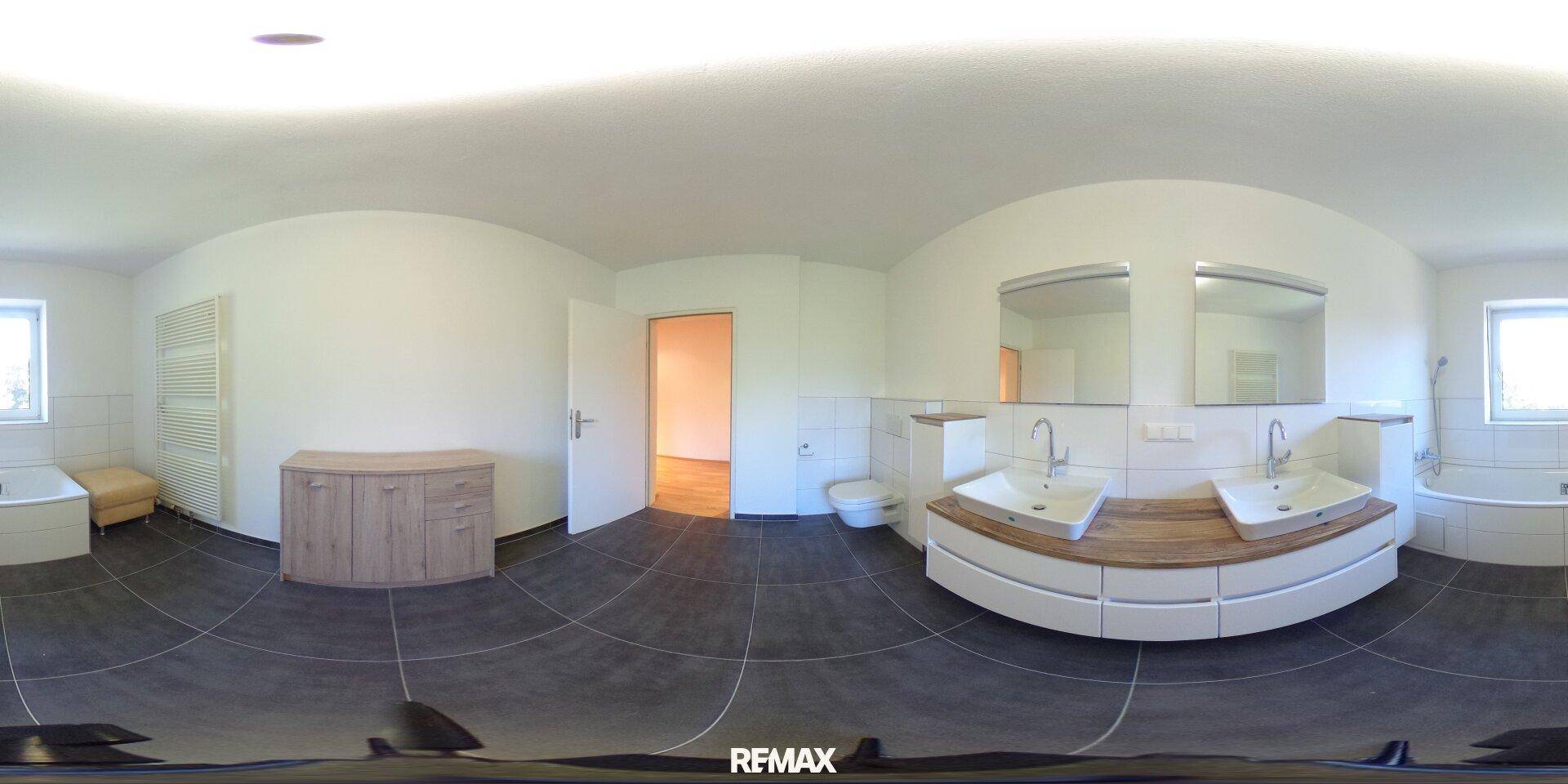Geräumiges Badezimmer mit Doppelwaschbecken, Badewanne und Fenster für Tageslicht.