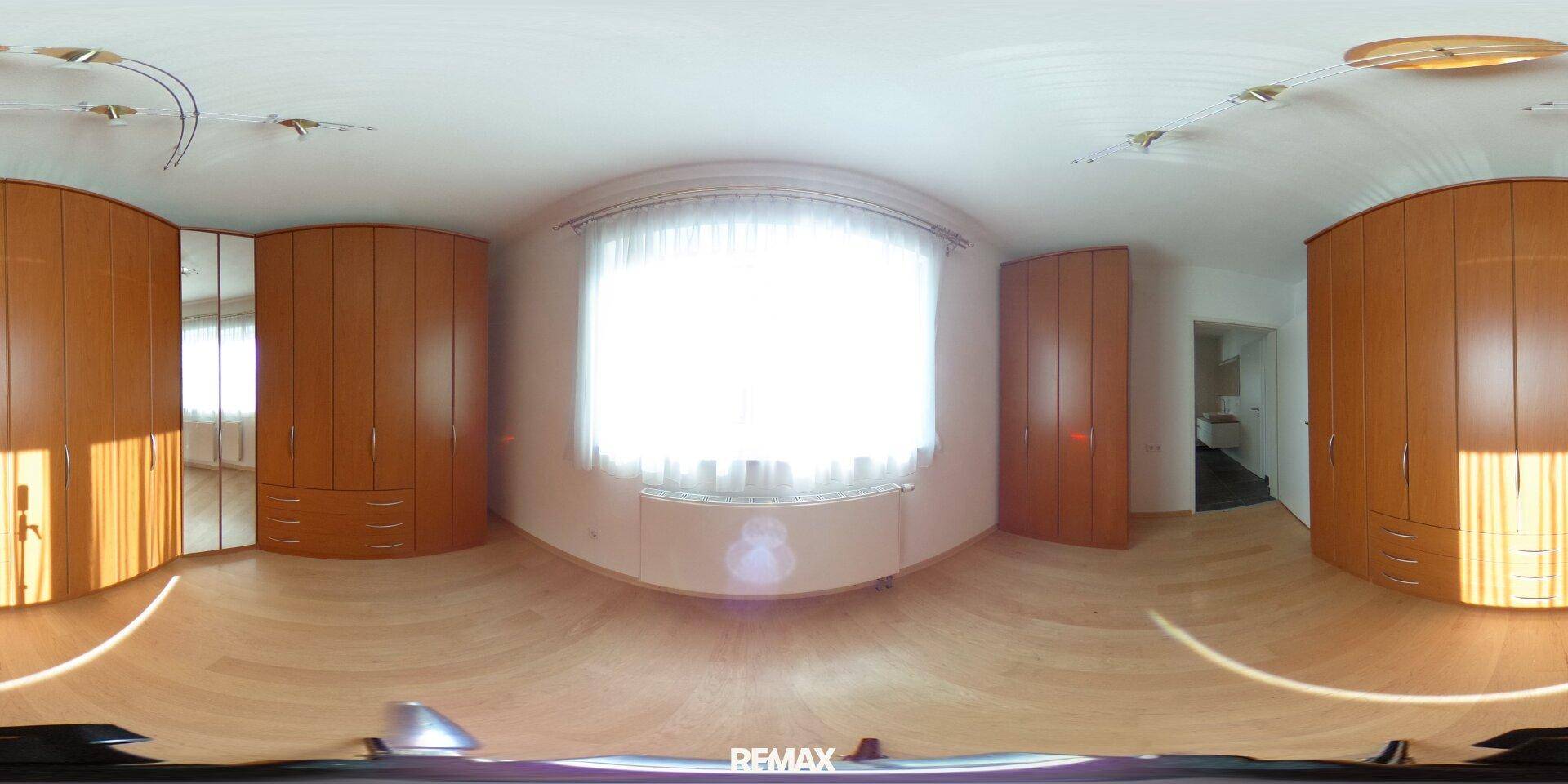 Helles Schlafzimmer mit Einbauschränken, Holzboden und großem Fenster.