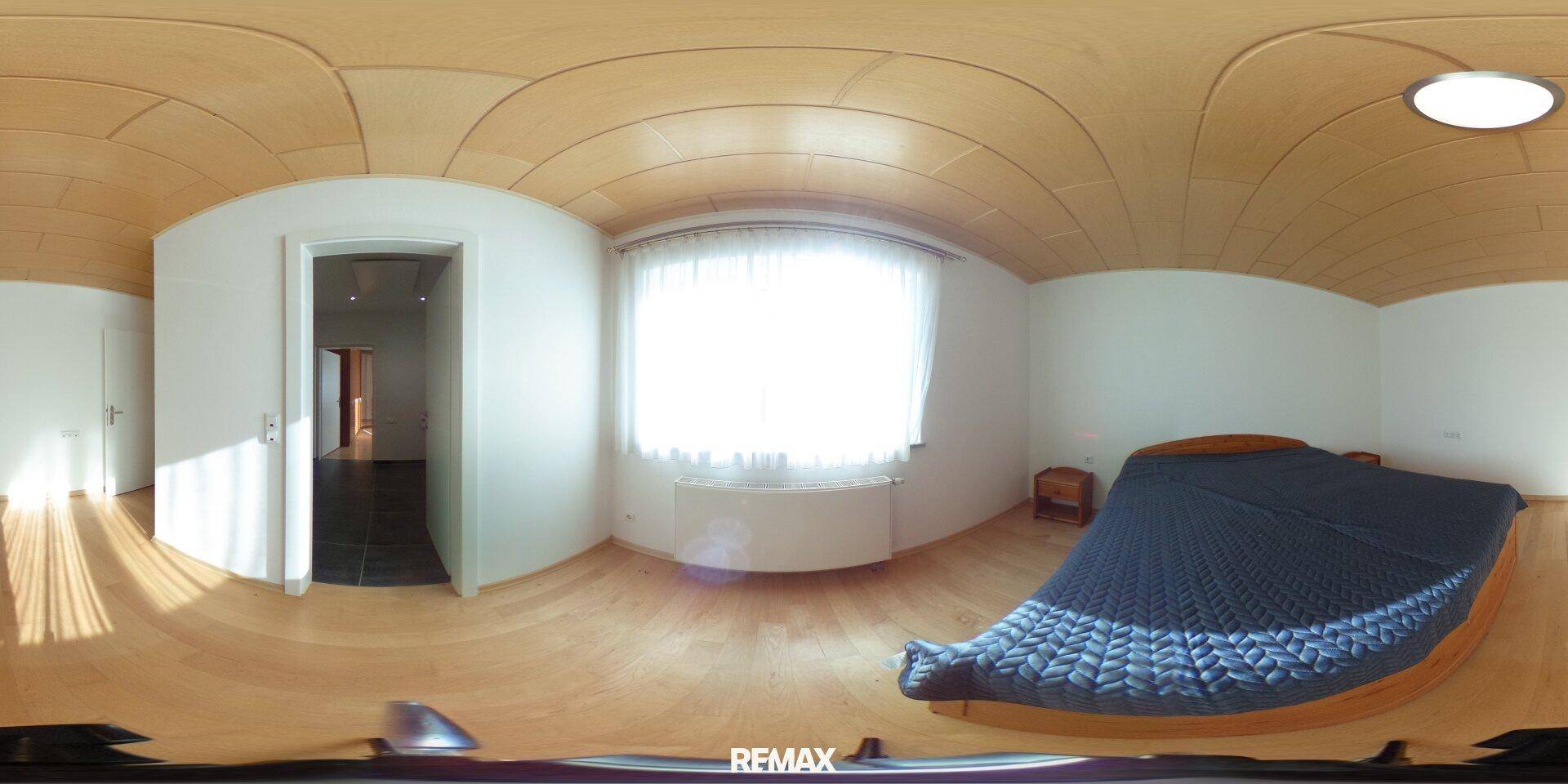Gemütliches Schlafzimmer mit Holzboden, Holzdecke und großem Fenster.