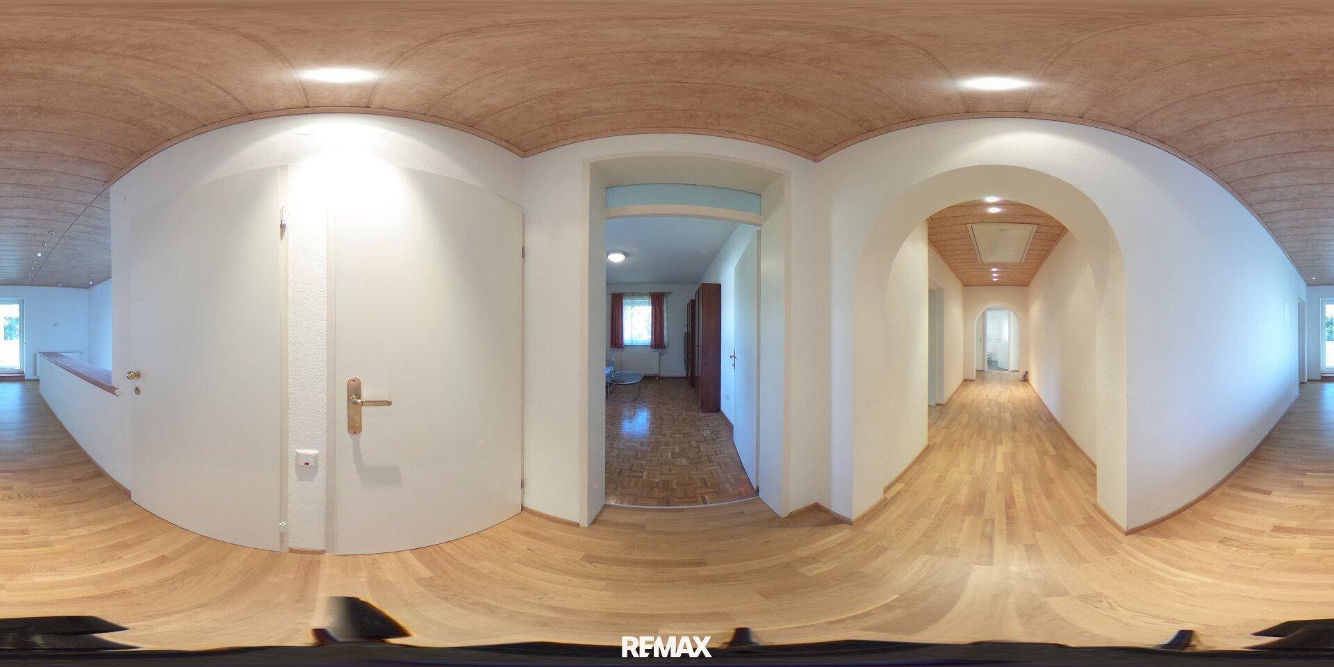 Heller Flur mit Holzboden und Holzdecke, der zu verschiedenen Räumen führt.