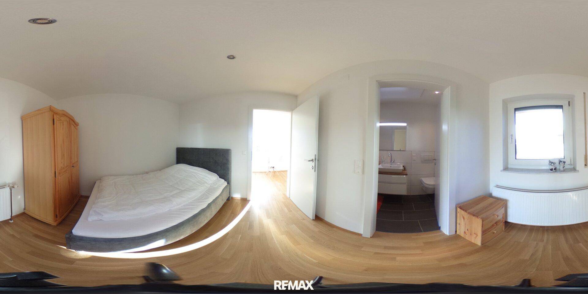 Schlafzimmer mit Holzboden, Kleiderschrank und direktem Zugang zum Badezimmer.