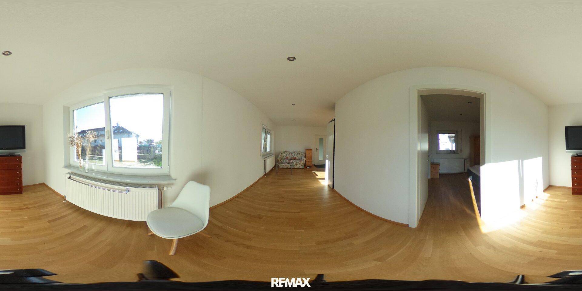 Helles Wohnzimmer mit Holzboden, großem Fenster und moderner Einrichtung.