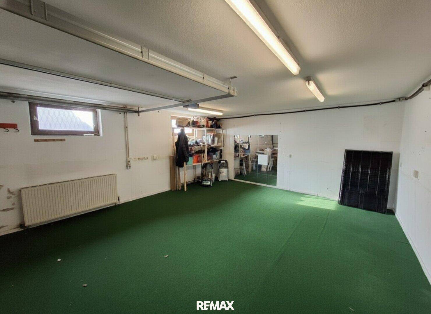 Geräumige Garage mit viel Stauraum und Fenster, ideal für Fahrzeuge und Lagerung.