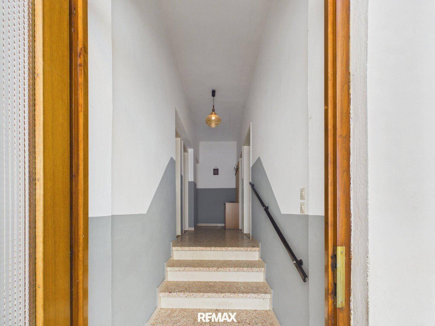 Eingangsbereich mit Treppe, zweifarbigen Wänden und einfacher Deckenleuchte.