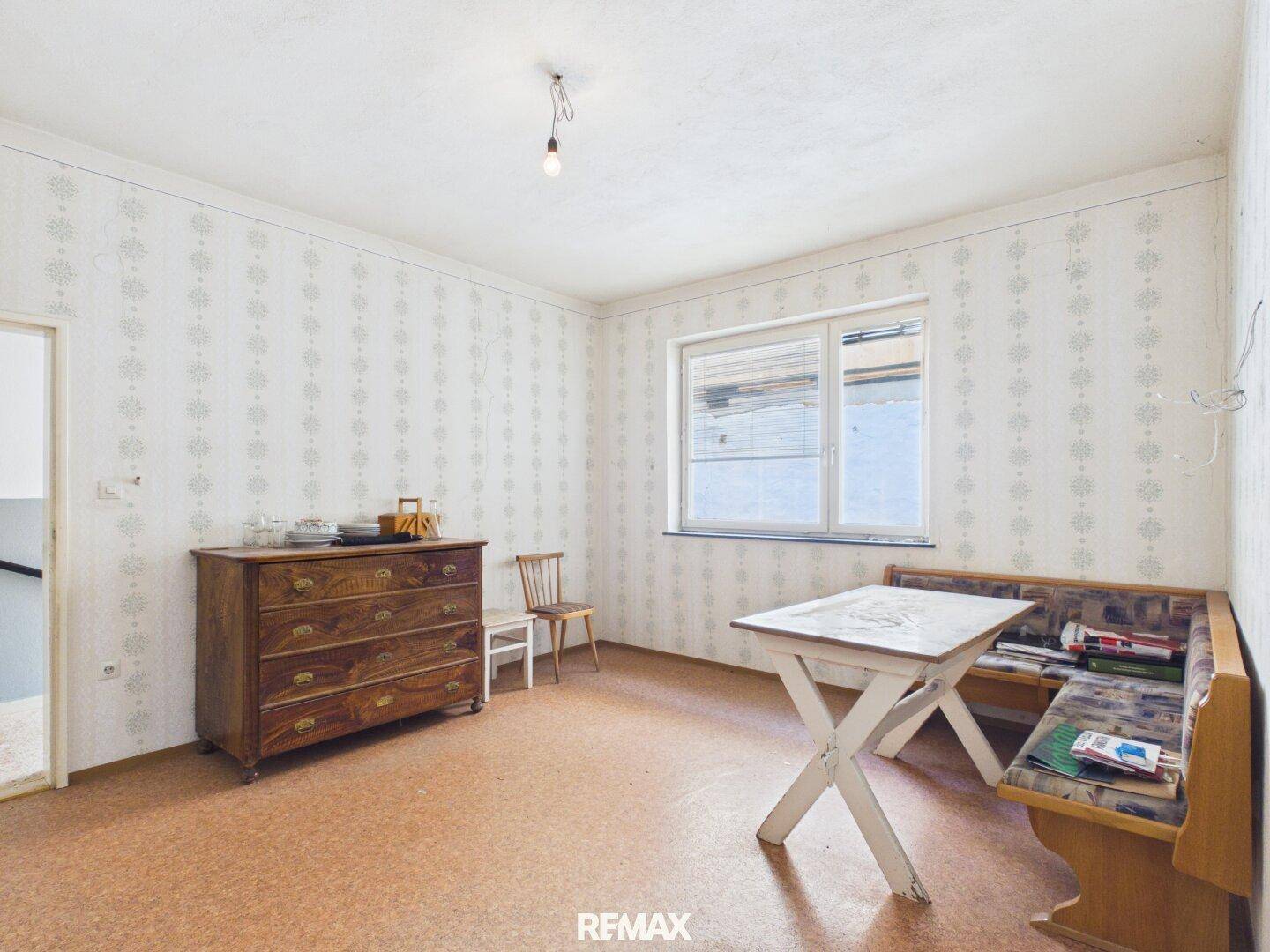 Esszimmer mit gemusterter Tapete, Holzkommode und gemütlicher Eckbank mit Tisch.