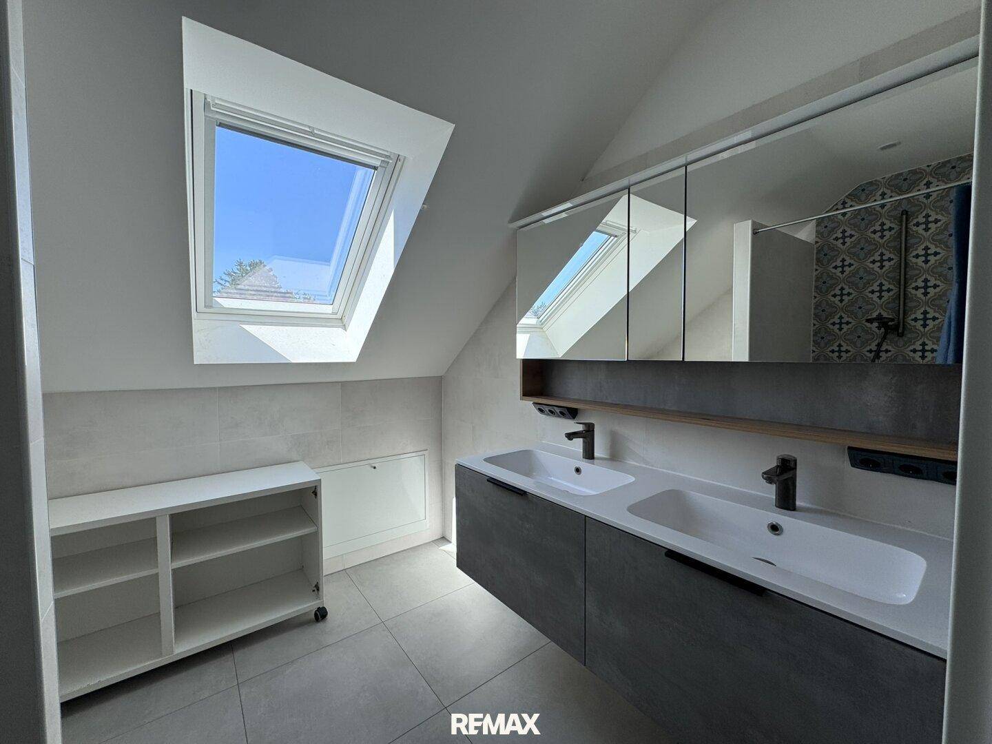Modernes Badezimmer im Dachgeschoss mit Doppelwaschbecken und Dachfenstern für viel Licht.