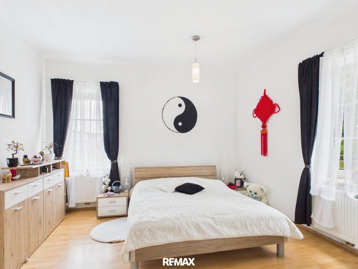 Helles Schlafzimmer mit Holzbett, Parkettboden und dekorativen Elementen an den Wänden.