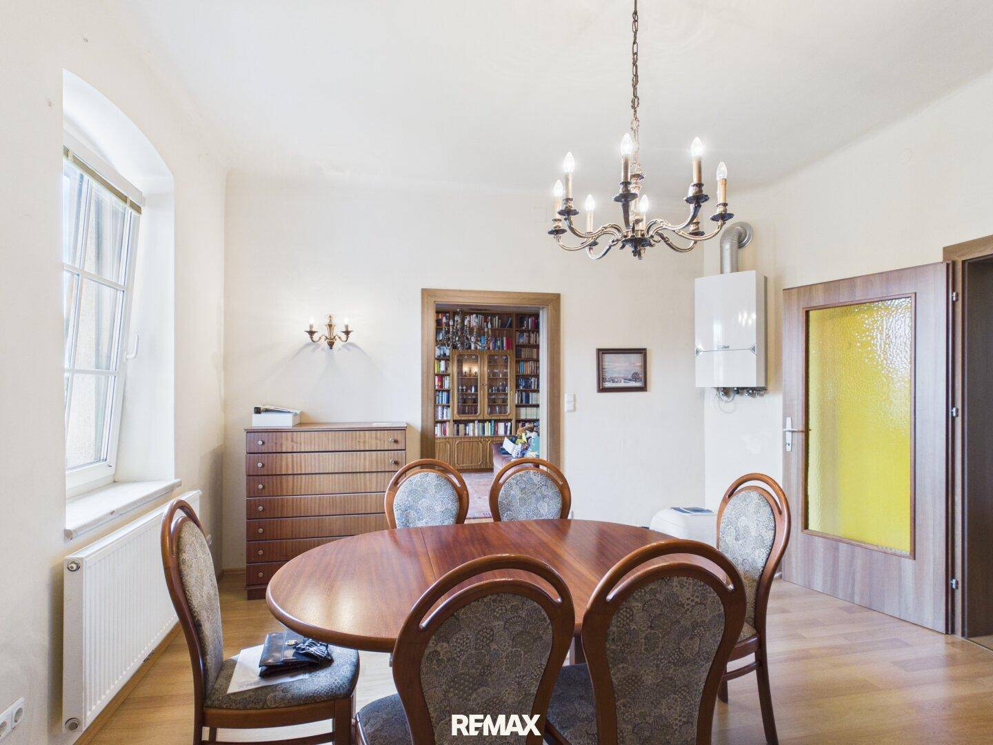Klassisches Esszimmer mit Holztisch, passenden Stühlen und einem Fenster für natürliches Licht.