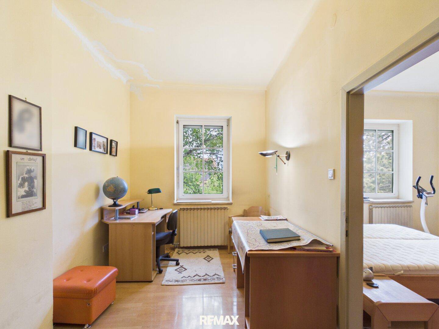 Funktionales Arbeitszimmer mit Schreibtisch, Holzmöbeln und einem Fenster mit Blick ins Grüne.