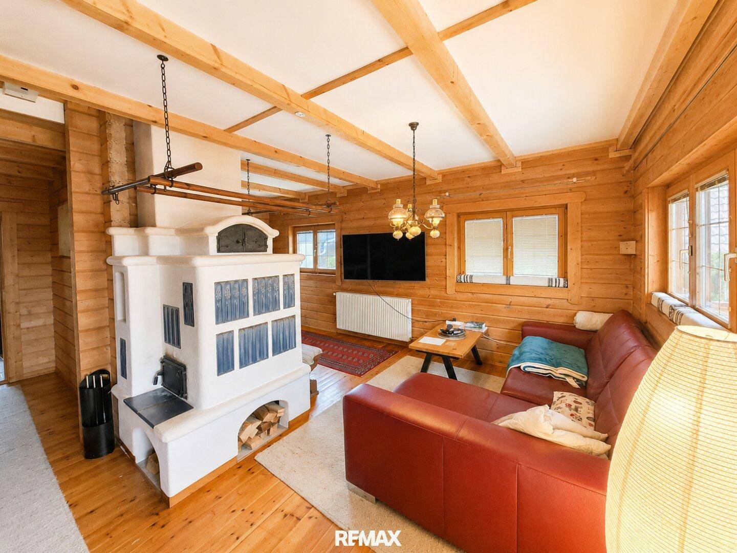 Geräumiges Wohnzimmer mit traditionellem Kachelofen, Holzbalken und gemütlicher Sitzecke.