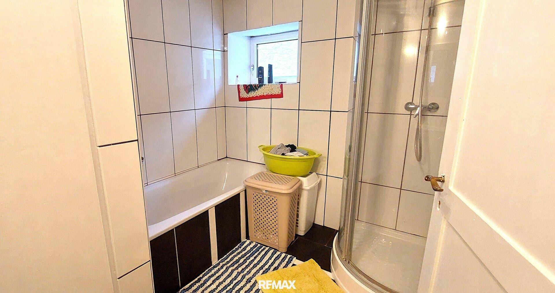Badezimmer mit Badewanne, Duschkabine und weiß gefliesten Wänden.