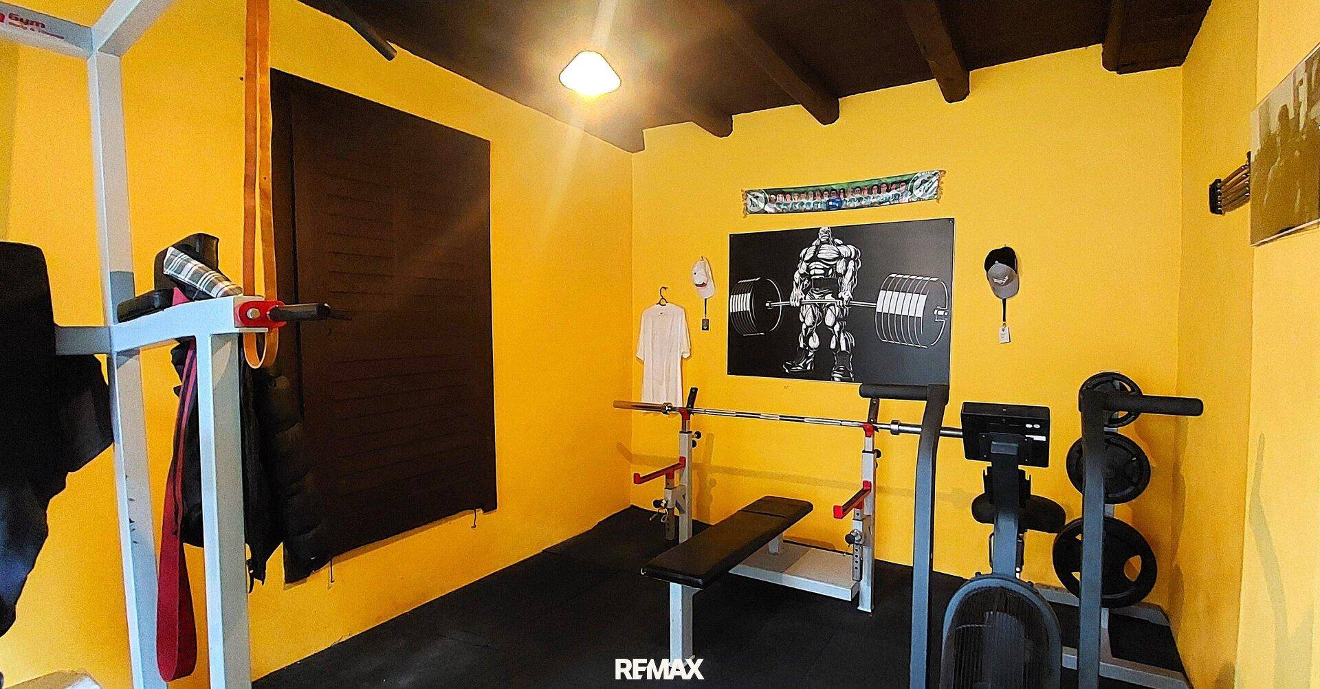 Heim-Fitnessraum mit gelben Wänden, Hantelbank und verschiedenen Trainingsgeräten.