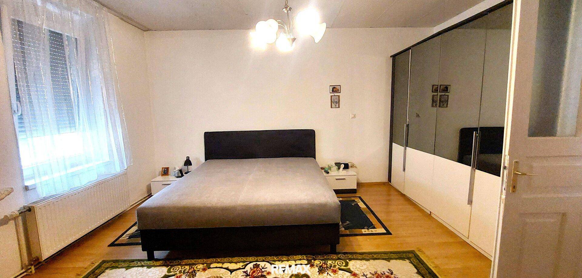 Helles Schlafzimmer mit Doppelbett, Spiegelschrank und Holzboden.