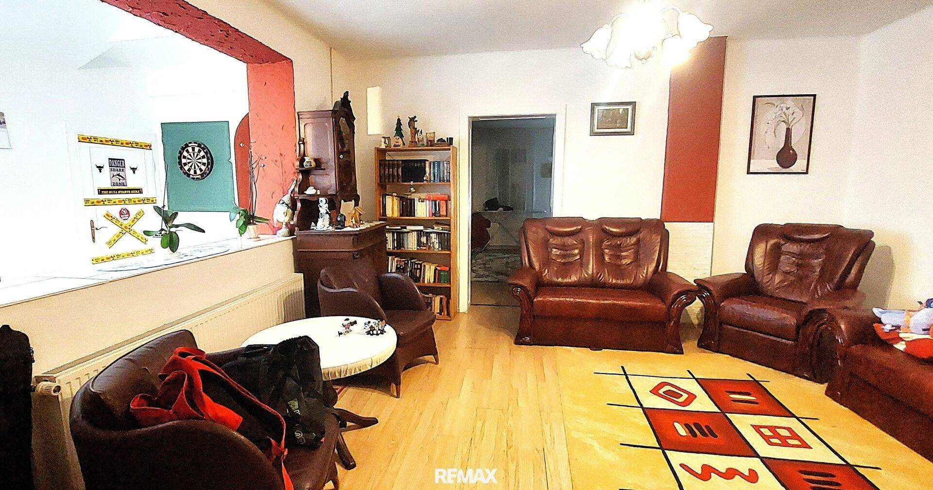 Wohnzimmer mit Ledersofas, Holzboden und einem Bücherregal.