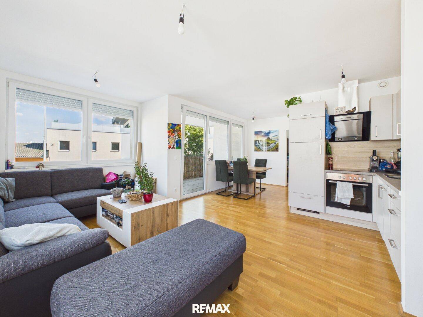 Geräumiger Wohnbereich mit Sofa, Esstisch und Zugang zum Balkon.
