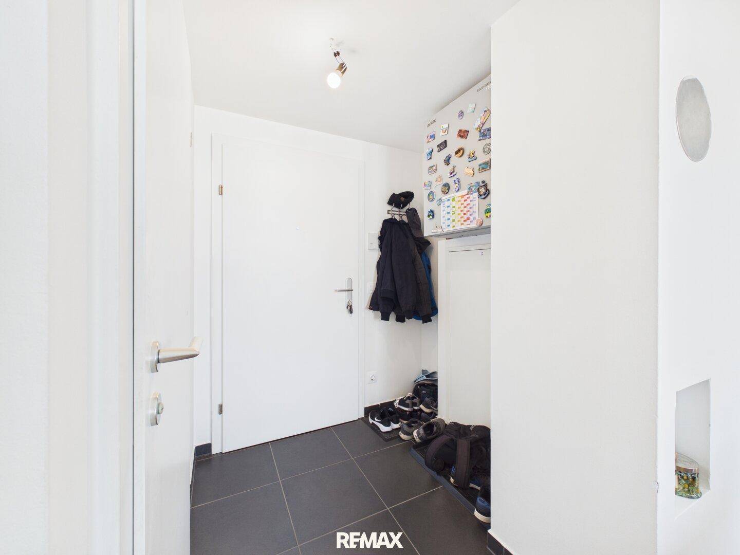 Eingangsbereich mit dunklen Fliesen, Garderobe und Schuhablage.