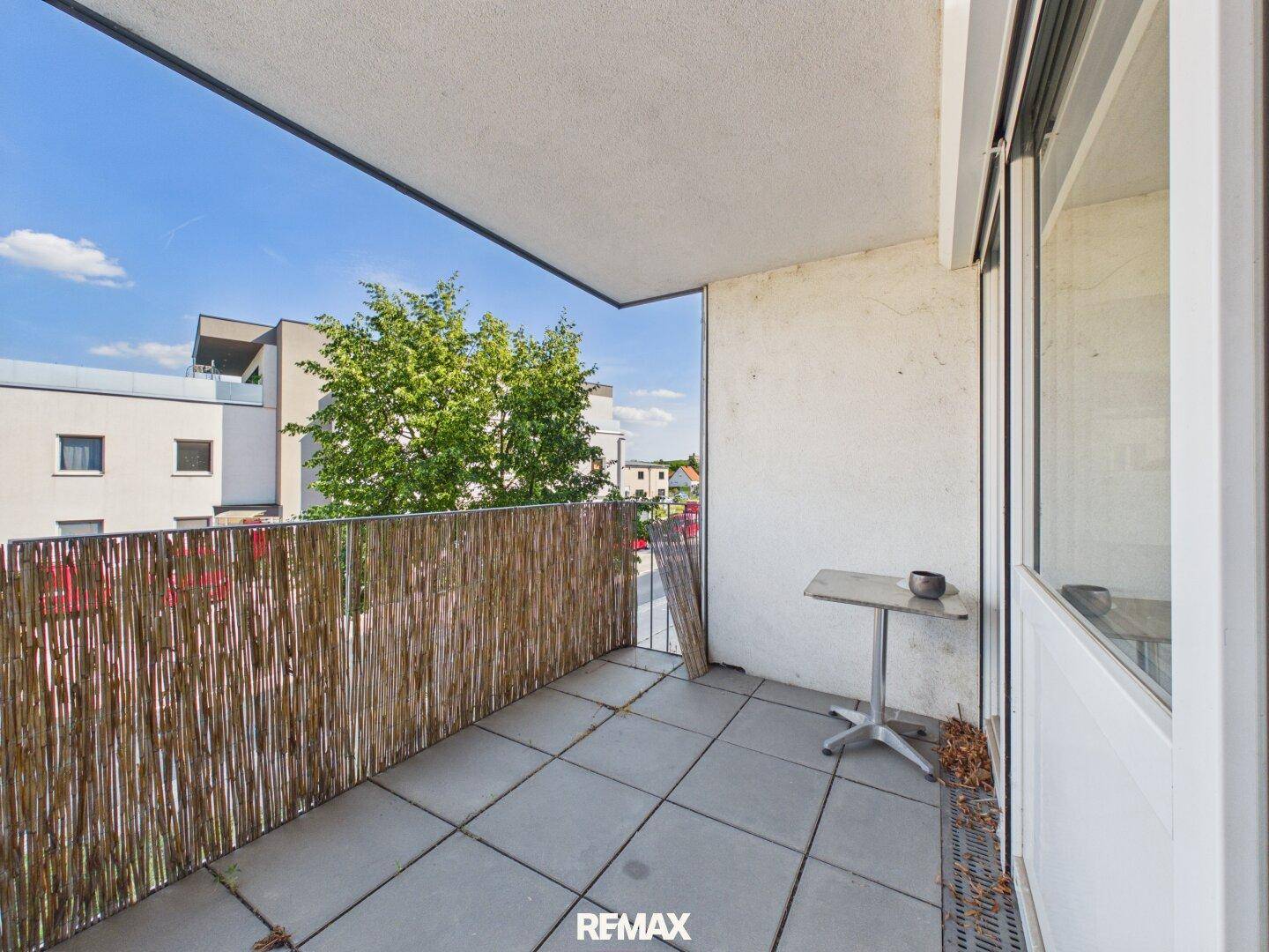 Überdachter Balkon mit Fliesenboden und Blick auf die Umgebung.