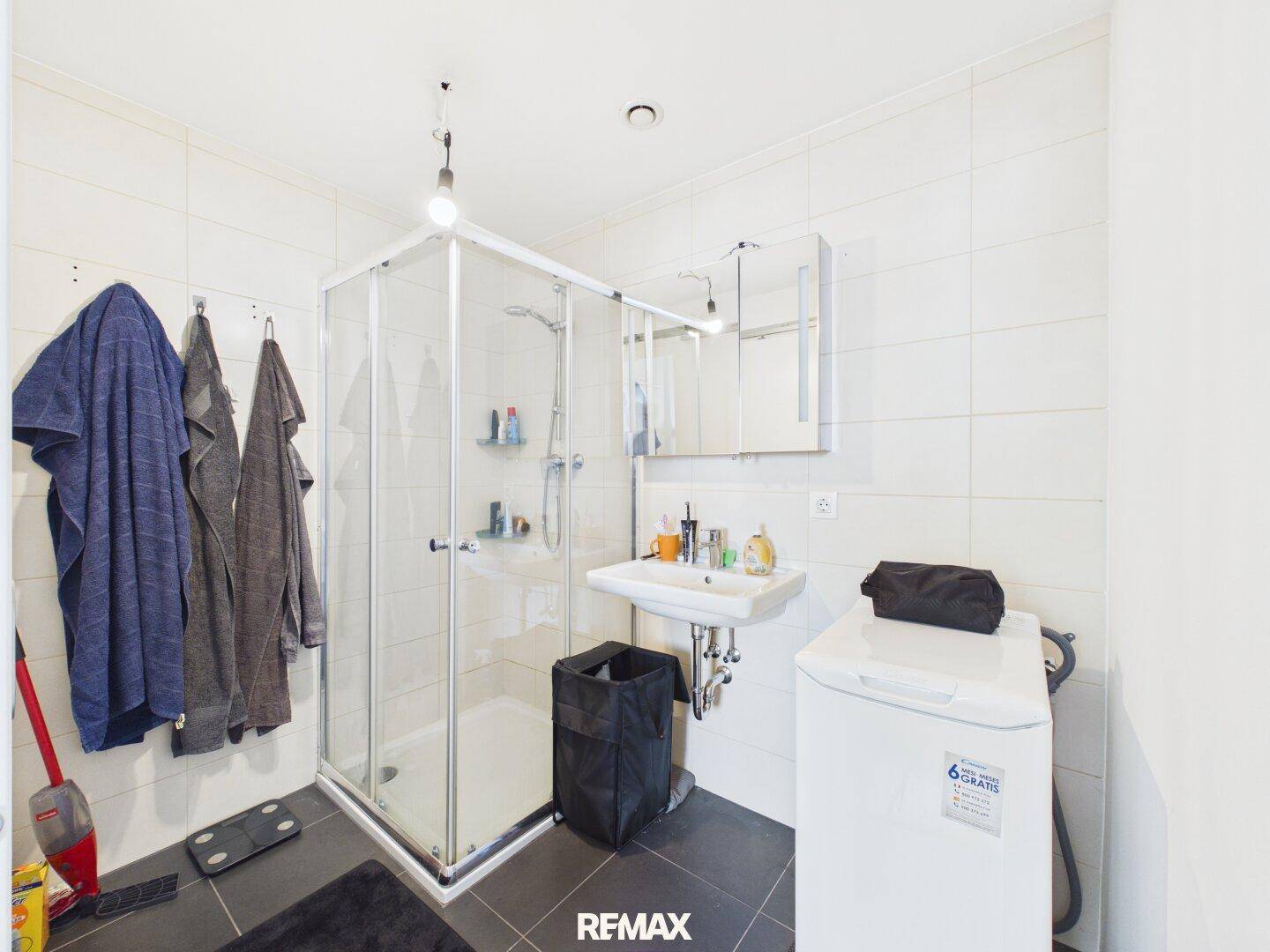 Modernes Badezimmer mit Duschkabine, Waschbecken und Waschmaschine.