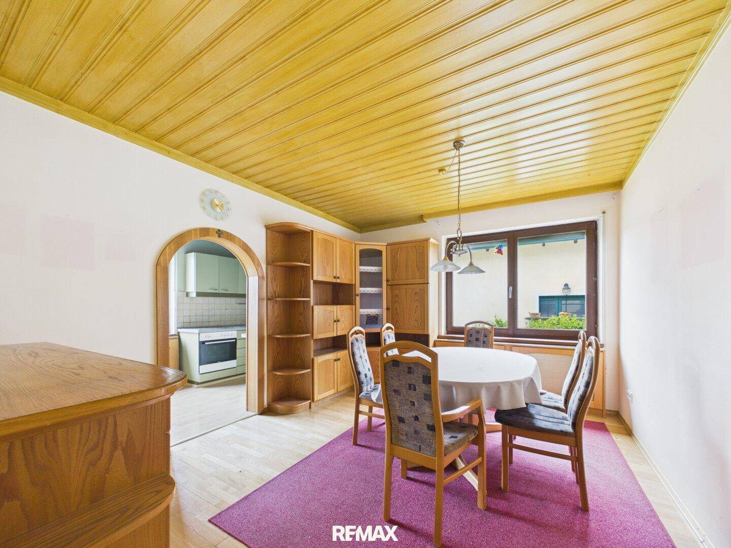 Gemütliches Esszimmer mit Holztäfelung an der Decke, Holzboden und Zugang zur Küche.